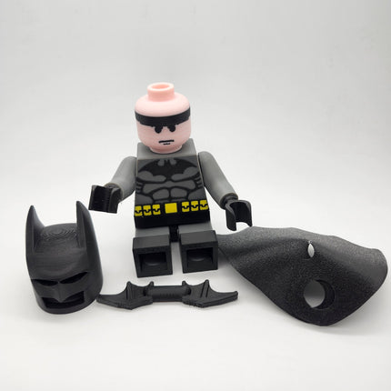 Batman-inspired brick-style figure with removable cowl cape and batarang accessories displayed separately