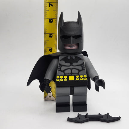 Oversized Batman-inspired brick-style display figure shown beside measuring tape