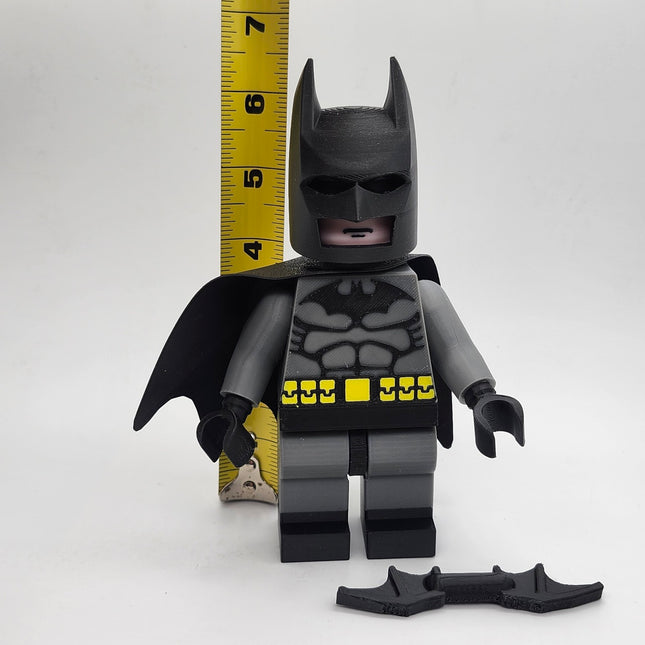 Oversized Batman-inspired brick-style display figure shown beside measuring tape