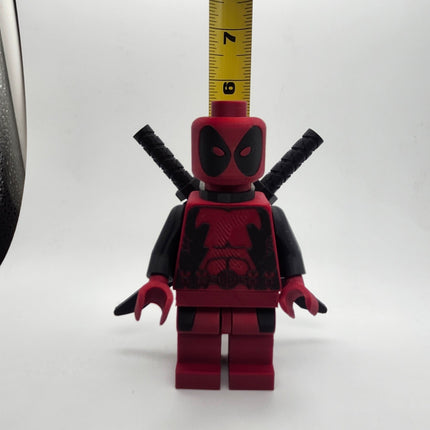 Deadpool inspired oversized brick figure shown with measuring tape at approximately 6 inches tall